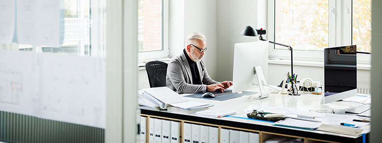 Ein Mann arbeitet am Computer in einem Büroraum.