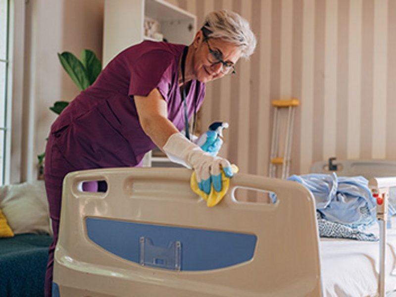 Eine Frau reinigt ein Kinder-Krankenhausbett.