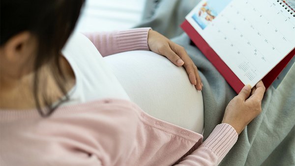 Eine Schwangere schaut in ihren Kalender.