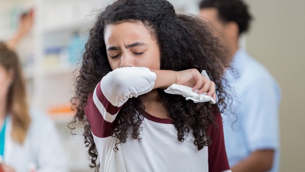 Ein Kind niest in die Armbeuge.