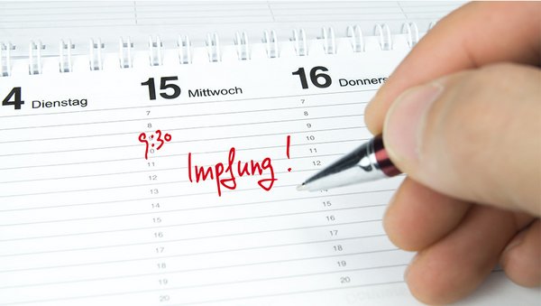 Eine Person trägt in ihren Kalender einen Impftermin ein.