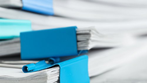 Ein Stapel von Akten, die mit einer Klammer zusammengehalten werden.