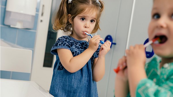 Kleinkinder putzen sich in einem Waschraum die Zähne.