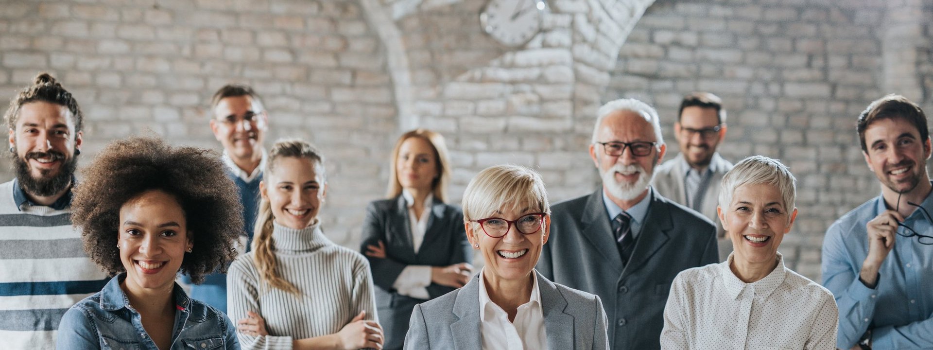 Mehrere Personen unterschiedlichen Alters und Geschlechts lächeln in die Kamera.
