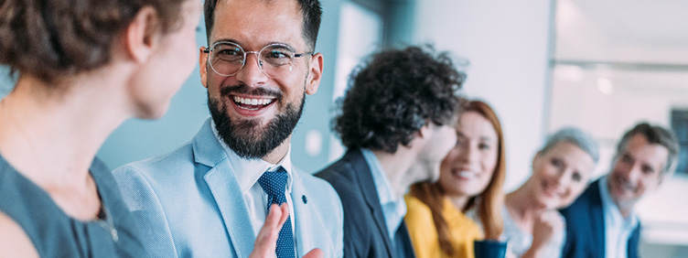 Mehrere Personen sitzen nebeneinander in einem Büroraum und unterhalten sich.