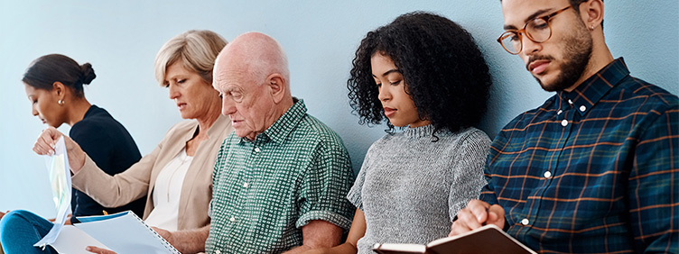 Personen in einem Wartezimmer, die lesen oder auf ihr Handy sehen.